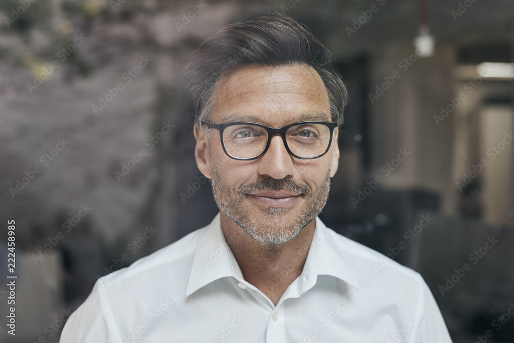 Portrait of man with stubble behind windowpane wearing white shirt and glasses Portrait of man with stubble behind windowpane wearing white shirt and glasses