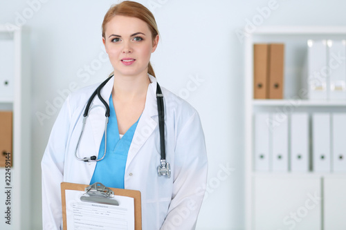 Beautiful female medical doctor standing at hospital. Physician is ready to help patients. Medicine and health care concept