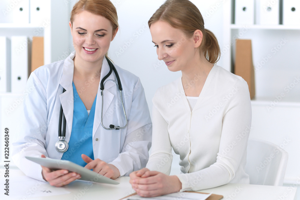 Doctor and patient are discussing something while sitting at the desk in hospital office, focus on cheerful smiling physician. Good news in medicine, health care concept Doctor and patient are discussing something while sitting at the desk in hospital office, focus on cheerful smiling physician. Good news in medicine, health care concept