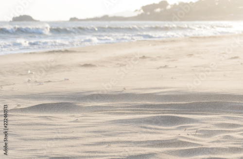 The end of a sunny and windy day at the Falconara beach in Sicily. In this shot is visible the sand moving fast with the strong air and the sun rays seeping into the frame in front of the sea water