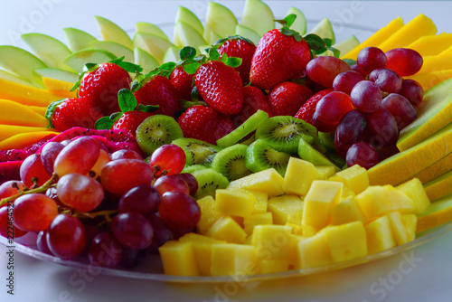 Fruit platter with fresh grapes, apple, pineapple, kiwi, mango, red ripe strawberry and pitaya. Colorful Fruit tray best health good food for party and holidays table.