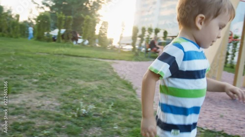 4k video of little toddler boy running after and catching flying soap bubbles inpark at sunset photo