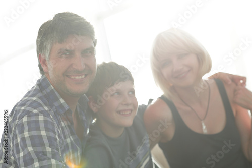 Parents and their son sit huddled in the living room and smiling