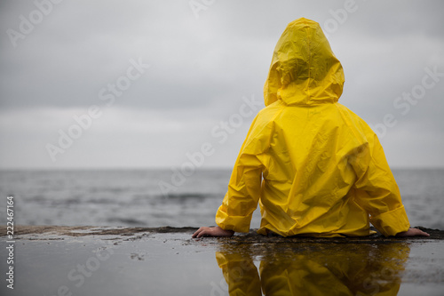 Rainy clouds. Child in a yellow raincoat.