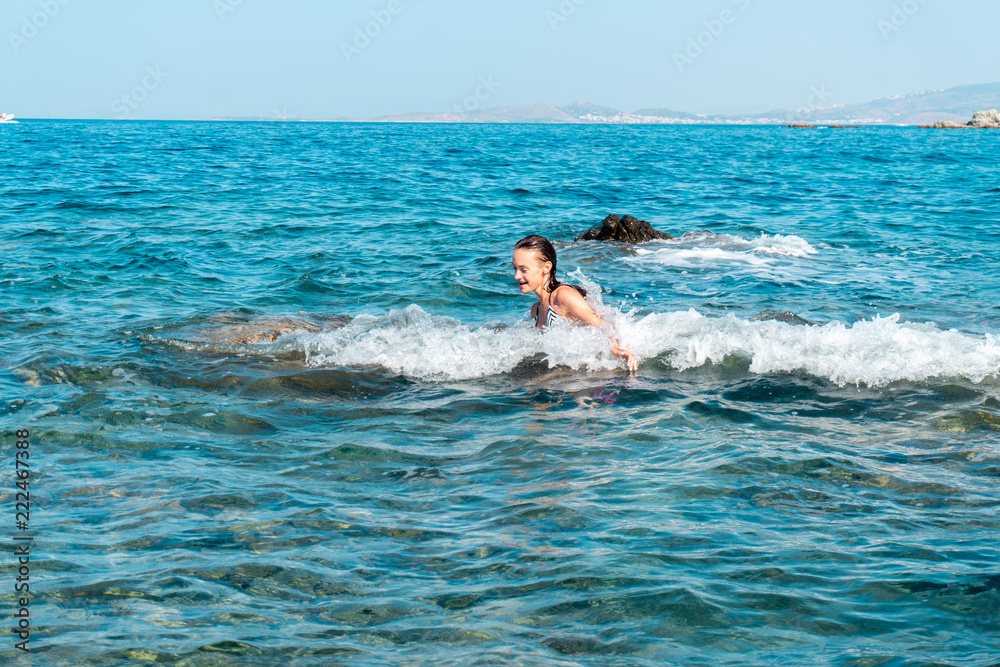 a cheerful young girl swims in the sea
