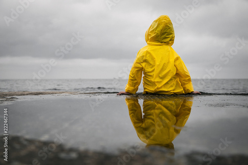 Photos Rainy clouds. Child in a yellow raincoat.