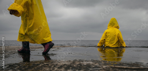  Rainy cloudy weather. Two children in yellow raincoats.