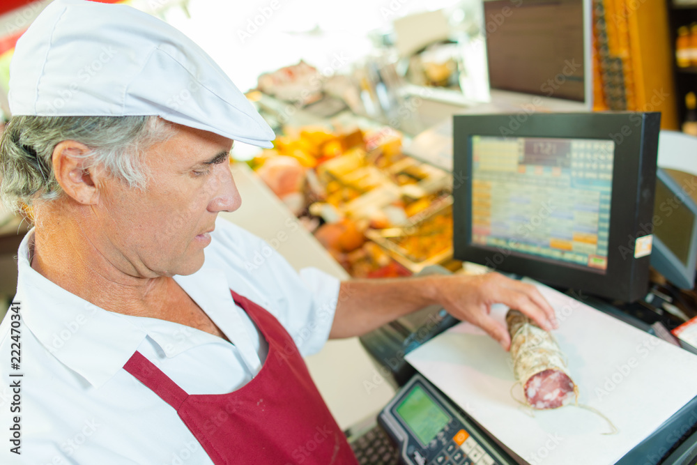 Butcher weighing cured meat StockFoto Adobe Stock