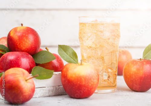 Glass of homemade organic apple cider with fresh apples in box on wooden background with sun light