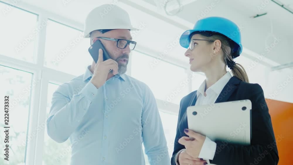 Engineers in hardhats have conversation in a factory Engineers in hardhats have conversation in a factory