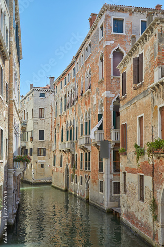 Venice canal with ancient buildings and houses facades in a sunny day in Italy