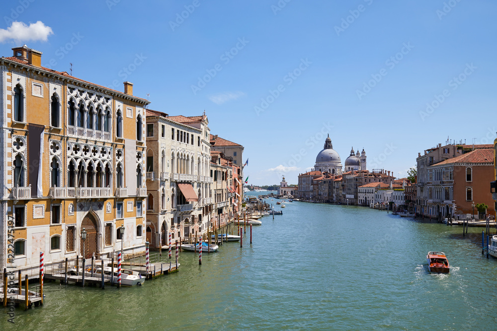 Grand Canal in Venice at midday with Saint Mary of Health basilica and motorboat in Italy
