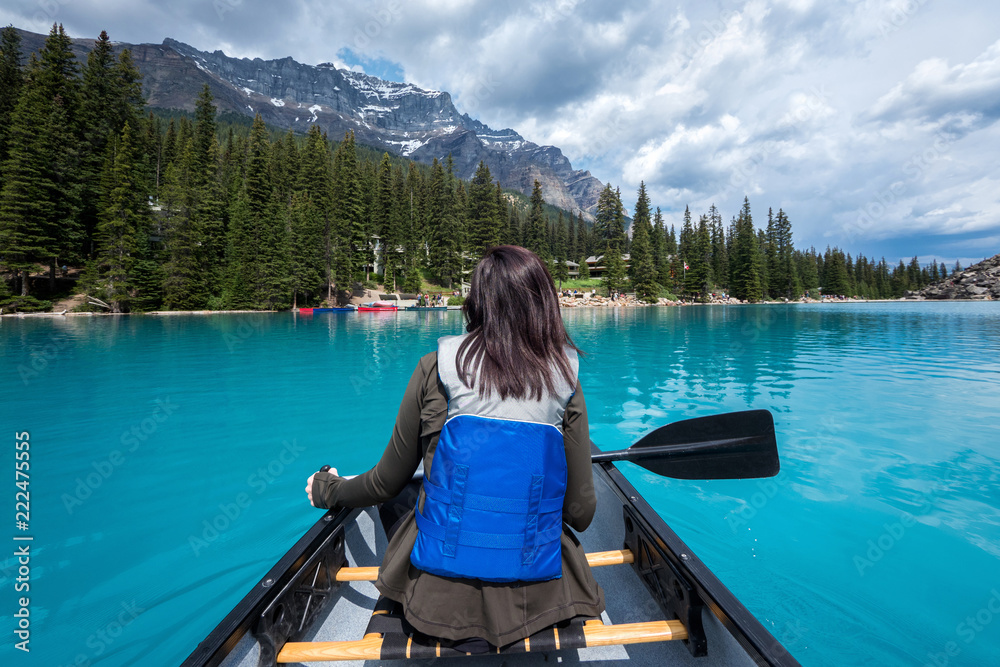 Female tourist canoeing on Moraine Lake in Banff National Park, Canadian Rockies, Alberta, Canada.