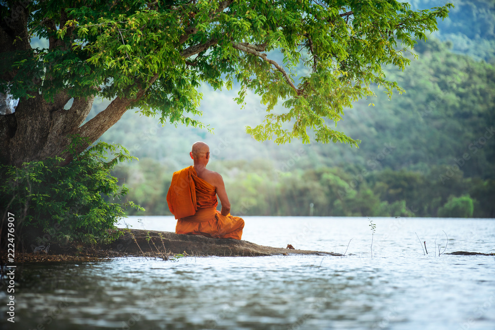 Buddhist monk in meditation beside the river with beautiful nature background - obrazy, fototapety, plakaty 