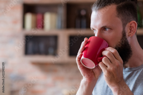 tea or coffee break and relaxing time concept. eating habits and energizing drink. bearded man having a cup of hot beverage in red mug.