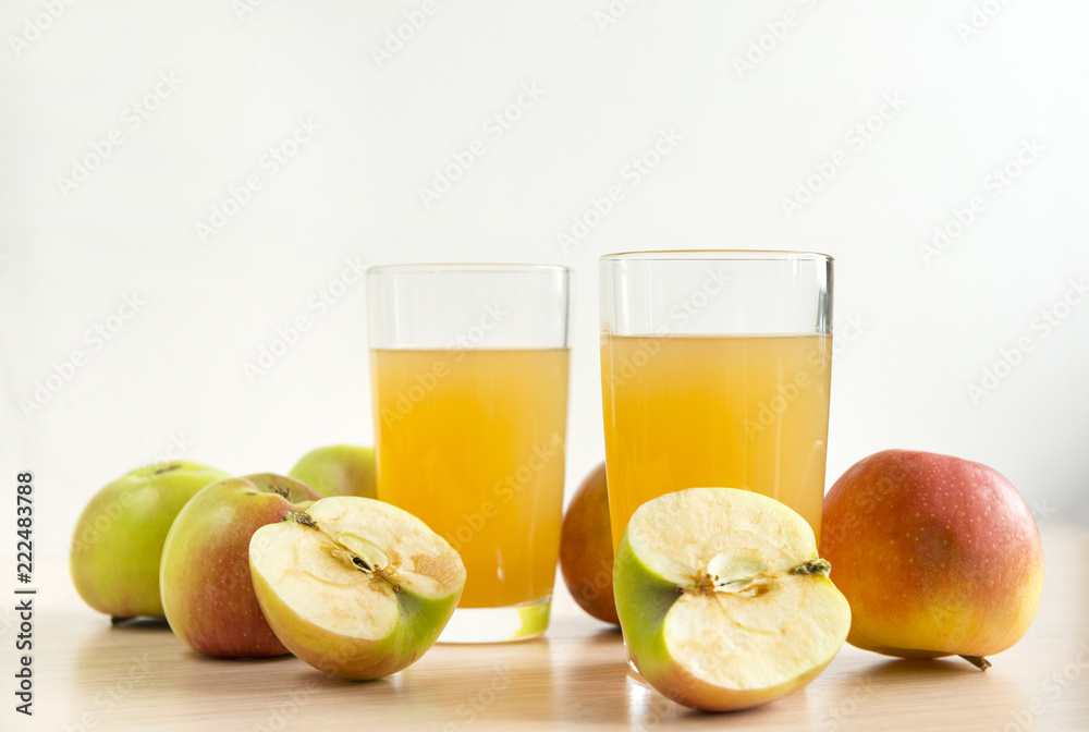 two 2 glasses of juice, Apple juice, whole apples and apples cut in half two 2 glasses of juice, Apple juice, whole apples and apples cut in half