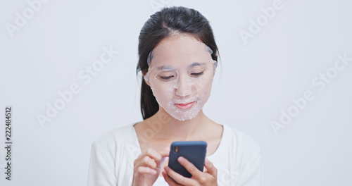 Woman apply mask and use of mobile phone at home