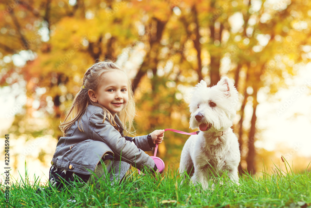 Little girl with dog in autumn park. Cute smiling girl having fun in walking with her pet. Happy child resting with dog outdoors. Autumn. Happy childhood. Little girl with dog in autumn park. Cute smiling girl having fun in walking with her pet. Happy child resting with dog outdoors. Autumn. Happy childhood.