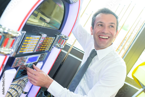 man selecting a song on old-fashion musical machine in bar photo
