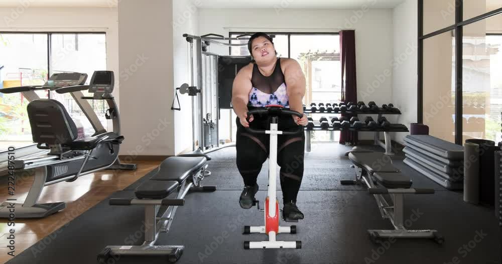 Exhausted overweight woman riding exercise bike in gym. Shot in 4k resolution Exhausted overweight woman riding exercise bike in gym. Shot in 4k resolution