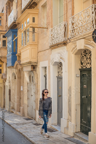 a young girl in lifestyle clothes strolling through the narrow streets of an ancient city with old doors and balconies