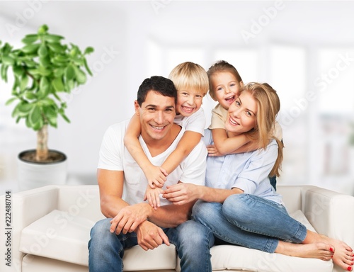 Beautiful smiling family sitting at sofa on room background