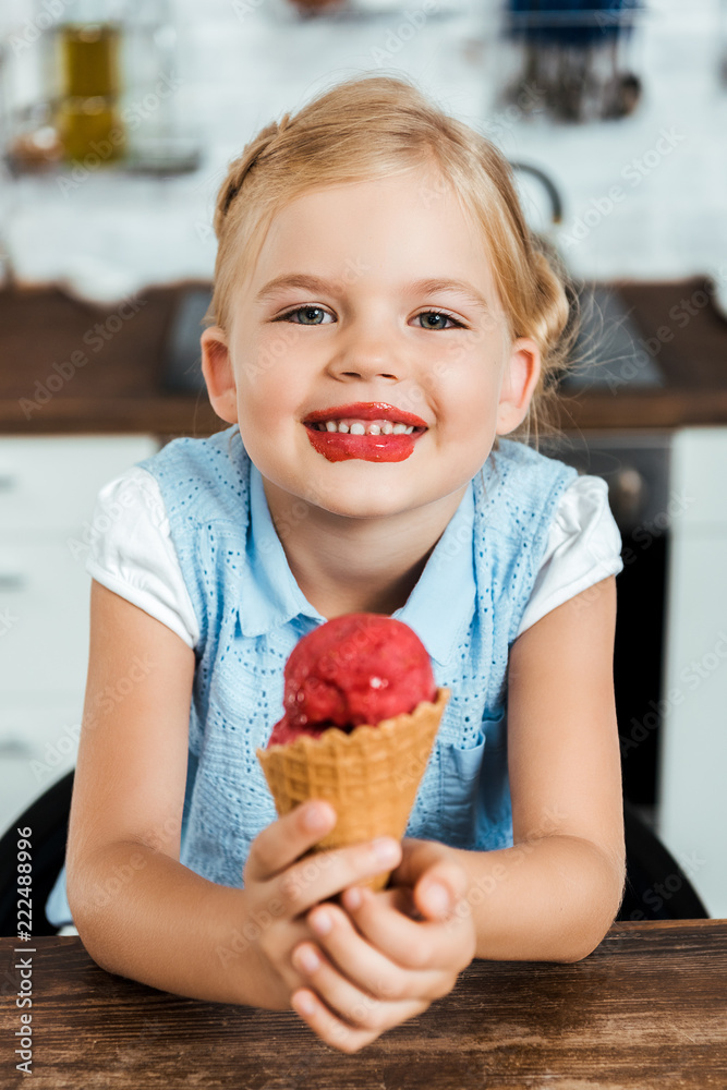 adorable happy kid holding delicious sweet ice cream cone and smiling at camera adorable happy kid holding delicious sweet ice cream cone and smiling at camera