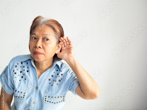 senior elderly asian women want to hear something from someone in white background maybe she have a problem about listening a sound need to see doctor or she hear shop sale in business or health care photo