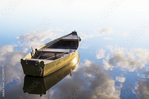 fishing boat in a calm lake water/old wooden fishing boat/ wooden fishing boat in a still lake water
