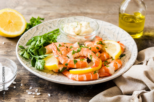 Grilled shrimps, parsley and lemon on wooden table