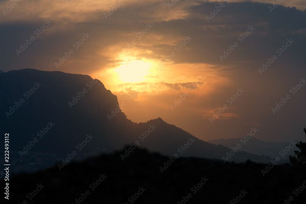 silhouette of a mountain against a dramatic sky background