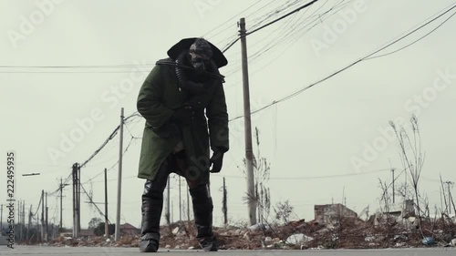 postapocalypse, lonely strong man walks amid garbage dump and abondoned town in special equipment for breath and old specticals. Polution enviroment and soon future. 4K photo