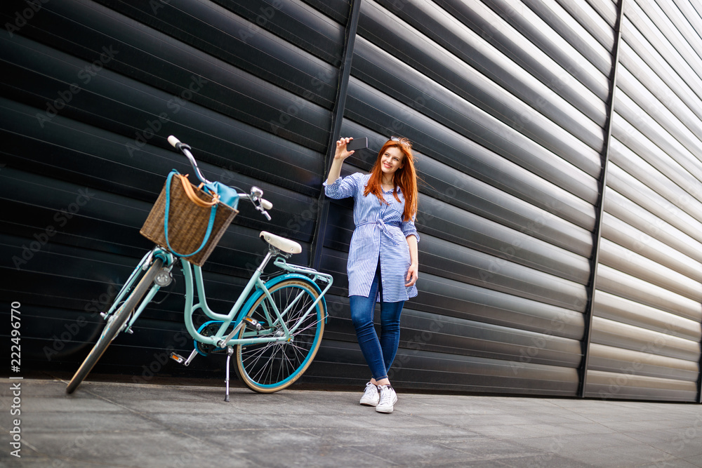 Obraz premium Urban female taking selfie in city near bike