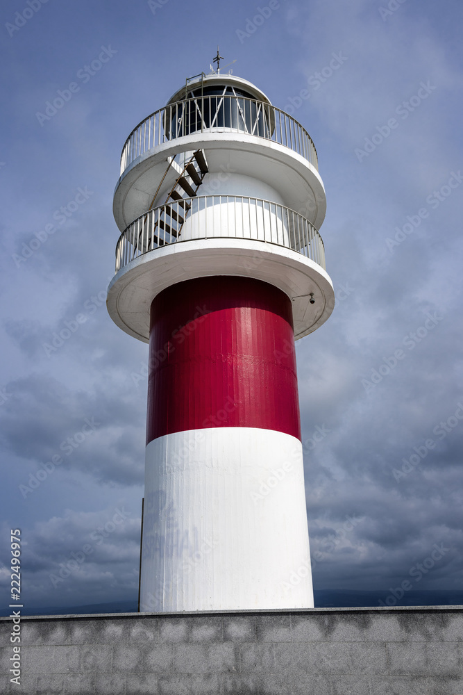 Beautiful red white striped lighthouse from below and blue cloudy sky in the background - concept nautical maritime danger navigation hazard ocean sea travel architecture building icon