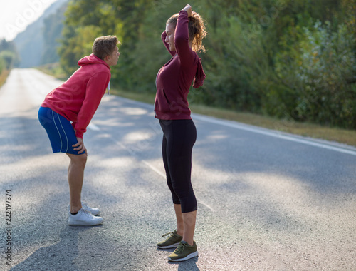 young couple warming up and stretching on a country road