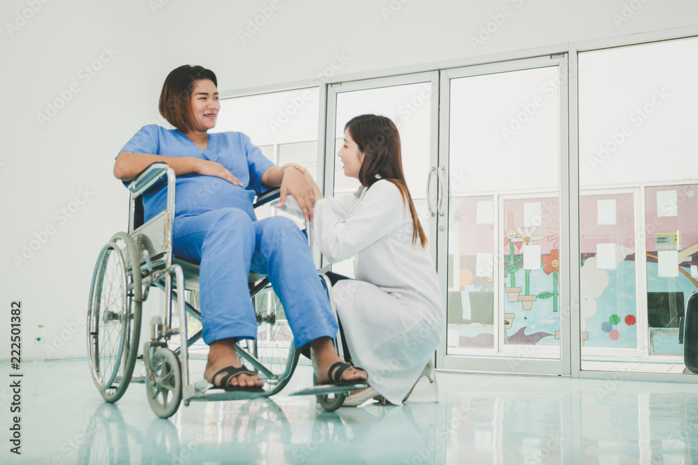 woman on wheelchair and her young caregiver smiling at each other, Nurse caring about woman woman on wheelchair and her young caregiver smiling at each other, Nurse caring about woman