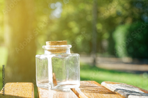 Bottle with coins stands on a park bench, transparent jar