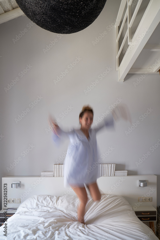 Blurred woman jumping on bed