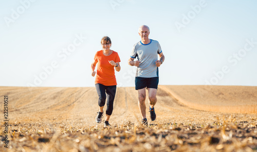 Senior Frau und Mann beim Jogging über ein Feld
