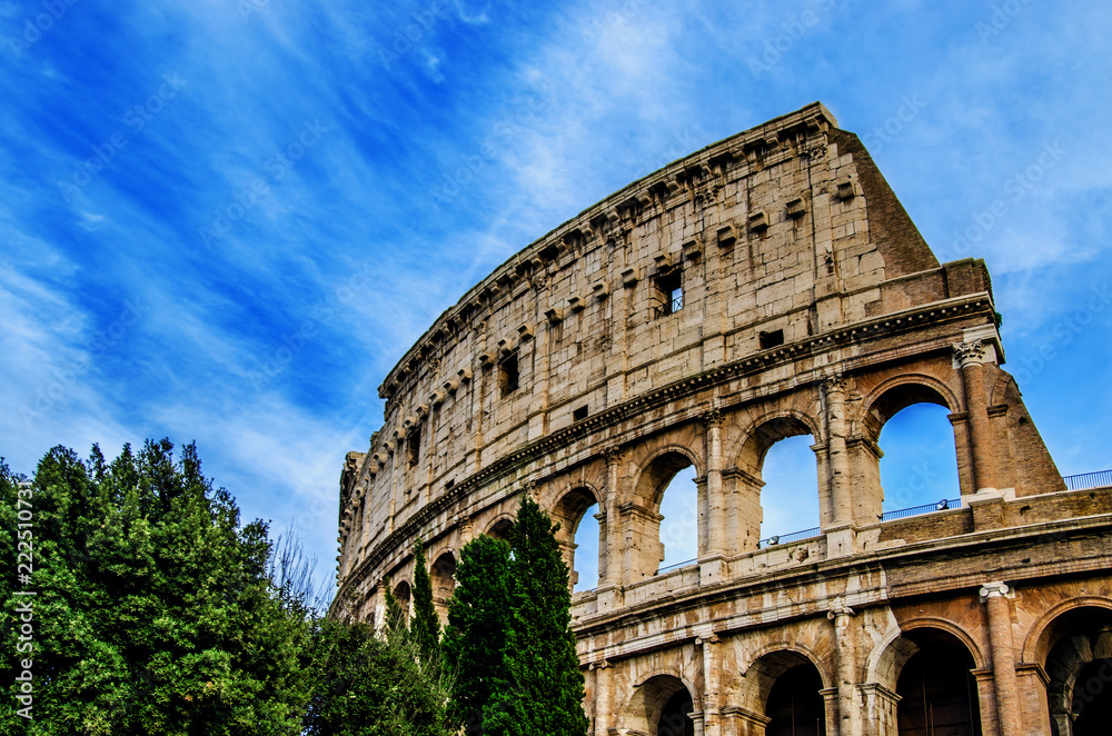 The ancient arches of the Colosseum against the blue sky with white traces from the floating clouds. Rome. Italy
