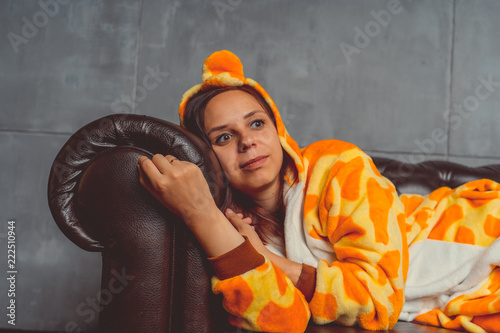 Happy teenage girl in funny nightclothes, pajamas cartoon style, positive face expression, on grey background. Emotional portrait of a girl on a sofa background. Crazy and funny man in a suit.