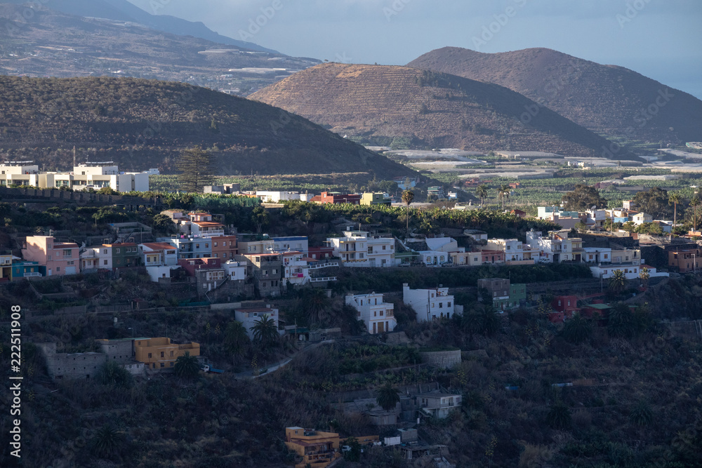 Fototapeta premium Colorful houses in the background of three volcanoes and a blue sky. La Palma Canary Islands