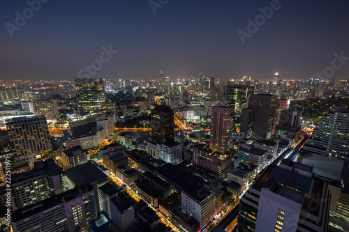 Scenic view of many lit skyscrapers and other buildings in downtown Bangkok, Thailand, from above at night.