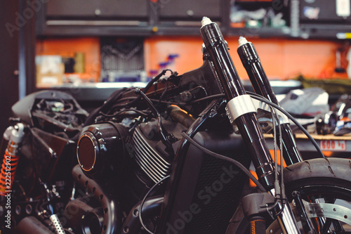 Many motorcycles on the floor with workshop tools, a modern garage, storage and repair. This bike will be perfect. repairing a motorcycle in a repair shop © lanarusfoto