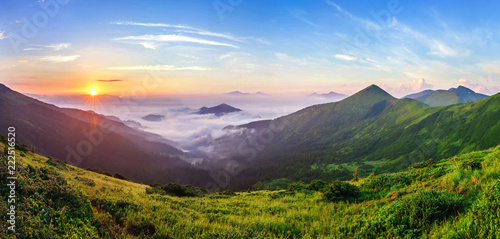 Beautiful sunrise in mountains with white fog below panorama © bilanol