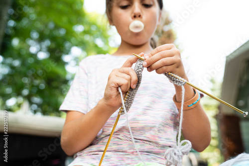 Close up of a girl blowing chewing gum while knitting