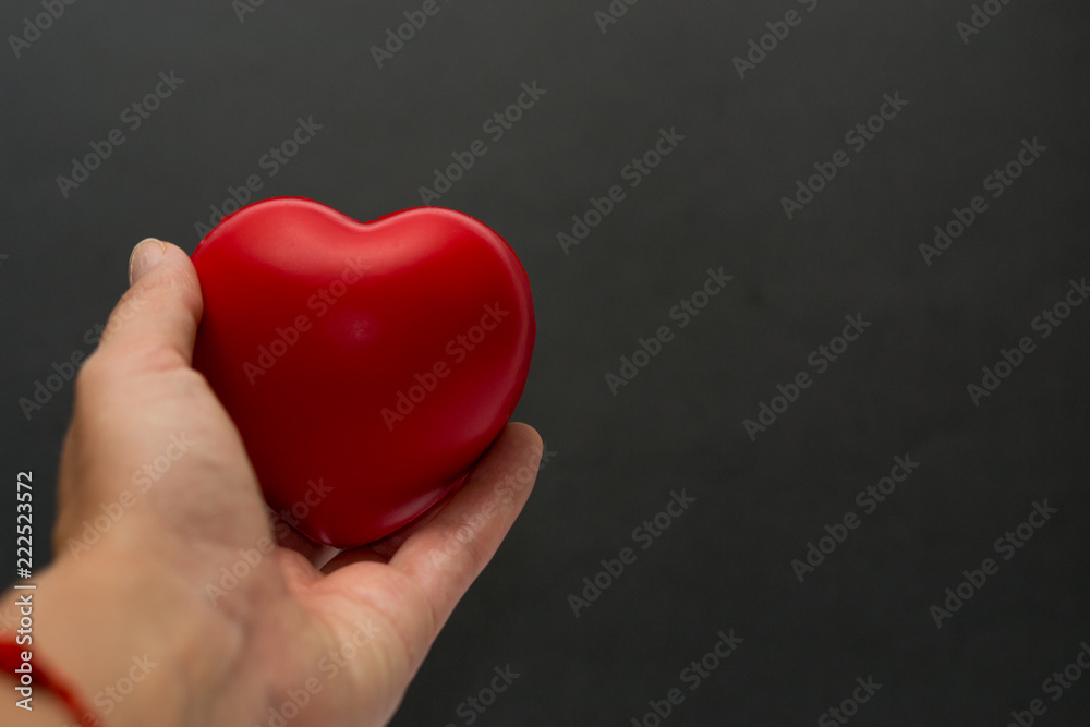 Close up red heart symbol of love isolated on black backgroound. Hand holds red heart. St. Valentines day. Objecr photography. Health and cardiovascular risk of diseases. Cardiology news. Close up red heart symbol of love isolated on black backgroound. Hand holds red heart. St. Valentines day. Objecr photography. Health and cardiovascular risk of diseases. Cardiology news.