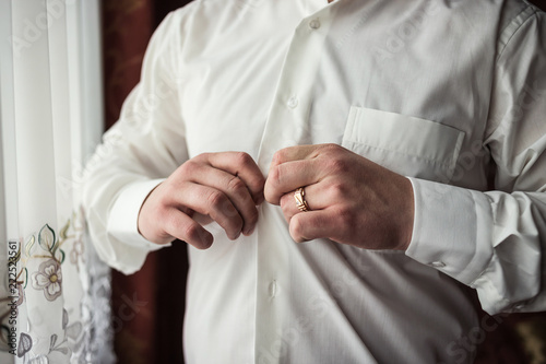 Businessman dresses white shirt, male hands closeup,groom getting ready in the morning before wedding ceremony