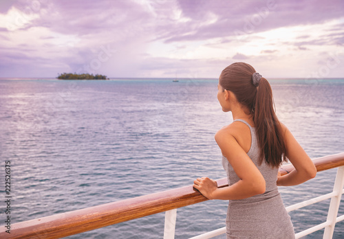 Luxury cruise vacation woman looking at exotic Tahiti landscape from boat deck at sunset. Elegant tourist young girl relaxing at view of ocean scenery outdoor. Sailing lifestyle holidays.