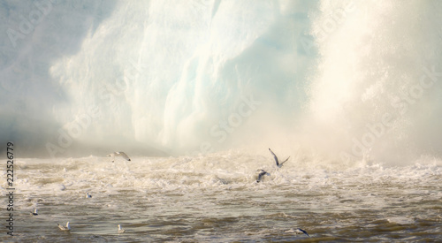 Dramatic Glacier Waterfall Scene with Churning Ocean and Glaucous Gulls Flying in the Arctic Ocean on the Coast of Spitsbergen Svalbard Archipelago in Northern Norway photo